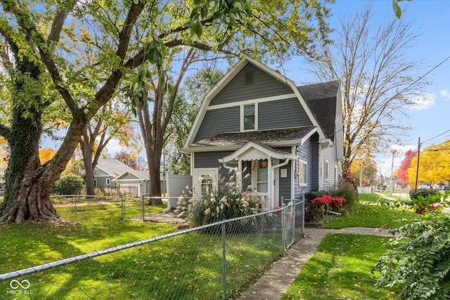 view of front of house with a fenced front yard, a gambrel roof, roof with shingles, and a front yard