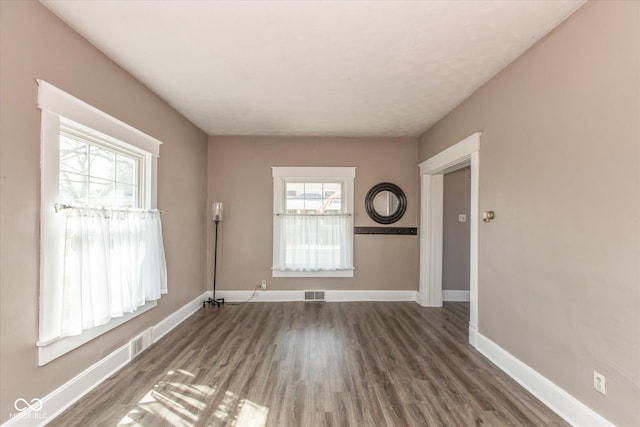 empty room with visible vents, baseboards, and wood finished floors