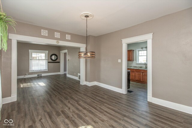 unfurnished dining area with a sink, dark wood-style floors, visible vents, and a wealth of natural light