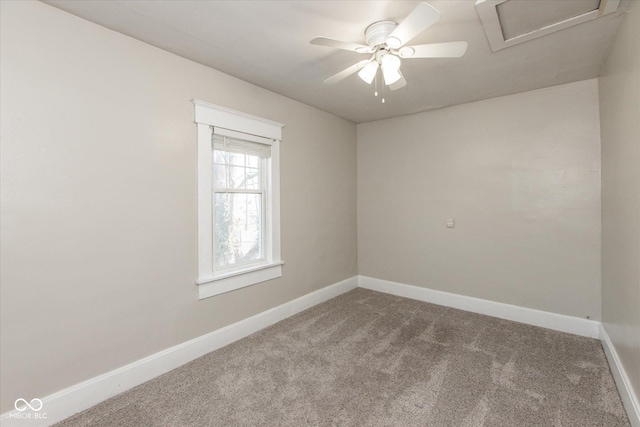 spare room featuring a ceiling fan, attic access, carpet, and baseboards