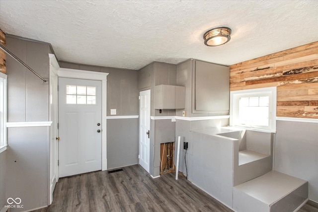 kitchen with visible vents, dark wood-style flooring, gray cabinetry, wood walls, and a textured ceiling