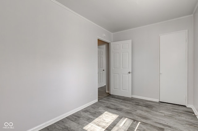 unfurnished bedroom featuring crown molding, baseboards, and wood finished floors