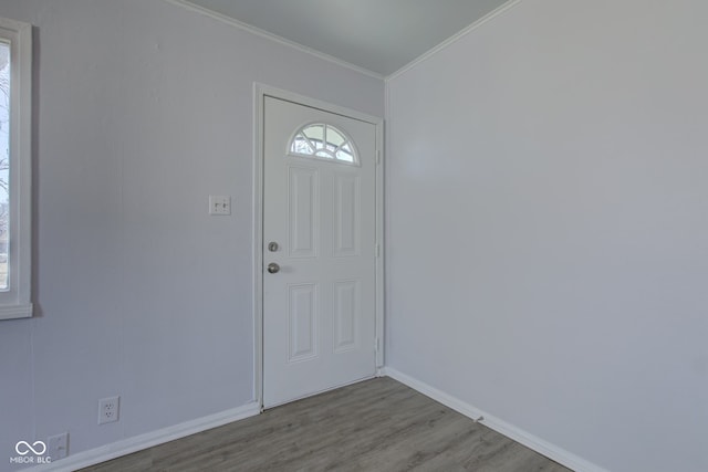 entryway with crown molding, wood finished floors, and baseboards