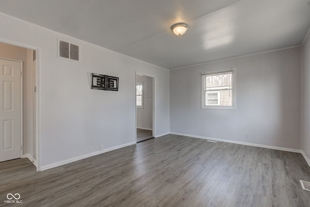 unfurnished room with baseboards, wood finished floors, visible vents, and ornamental molding