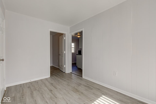 spare room with baseboards and light wood-style floors