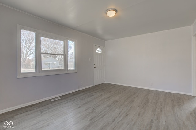 foyer entrance with visible vents, baseboards, wood finished floors, and ornamental molding