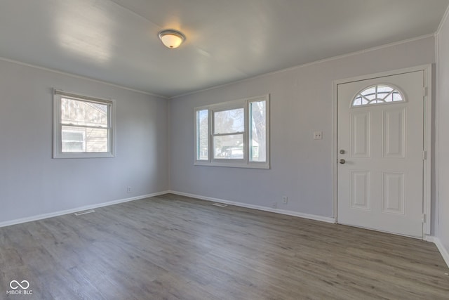 foyer with a healthy amount of sunlight, wood finished floors, and ornamental molding