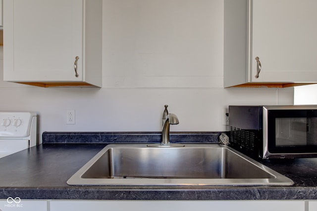 kitchen featuring white cabinetry, dark countertops, and a sink