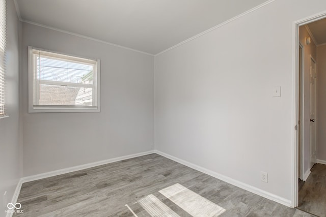 spare room with baseboards, wood finished floors, and ornamental molding