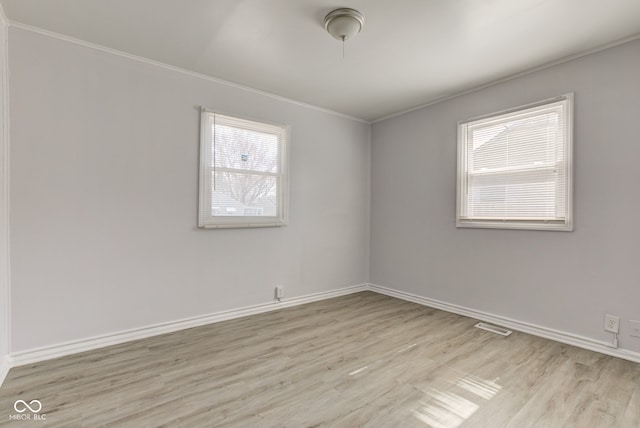 spare room with light wood-type flooring, baseboards, a healthy amount of sunlight, and visible vents