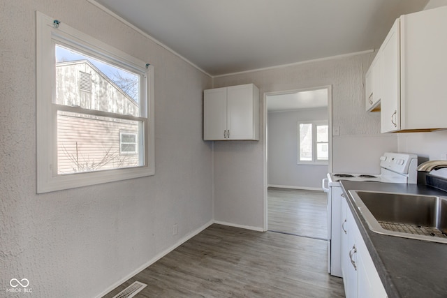 kitchen with white cabinets, ornamental molding, wood finished floors, and white range with electric cooktop