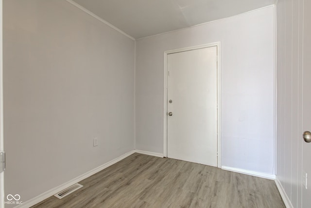 unfurnished room featuring visible vents, baseboards, light wood-style floors, and ornamental molding