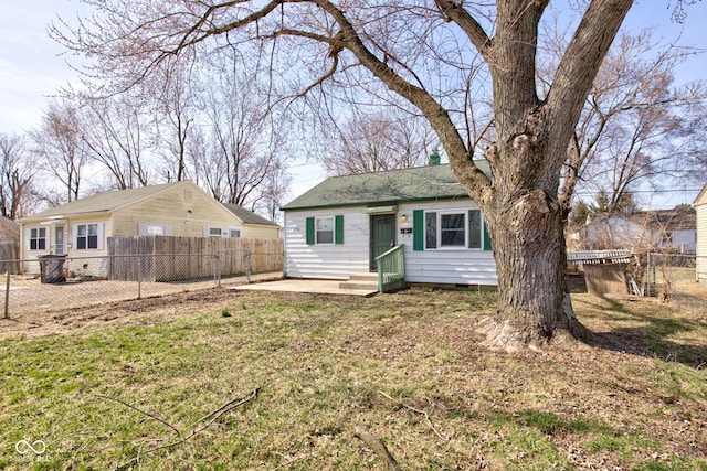 rear view of house with entry steps, fence, a lawn, and crawl space