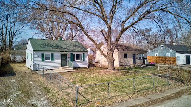 view of front facade featuring an outdoor structure, a front lawn, a fenced backyard, and a shingled roof