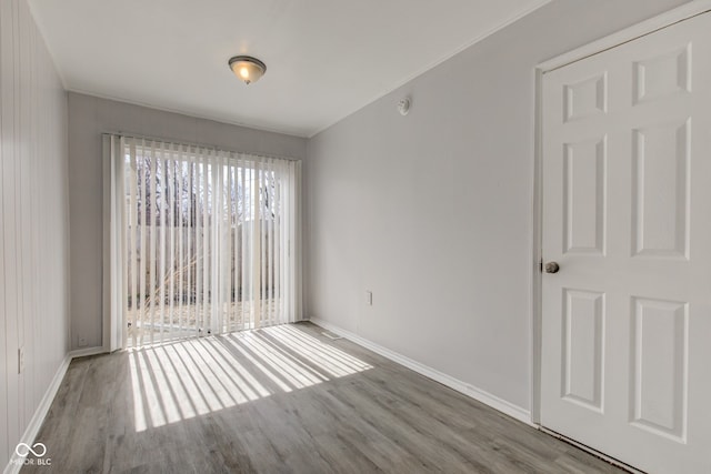 empty room with baseboards, wood finished floors, and ornamental molding