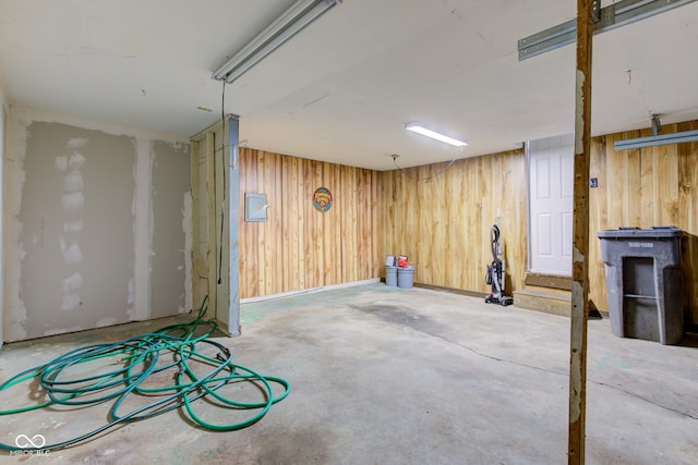 finished basement with electric panel and wood walls