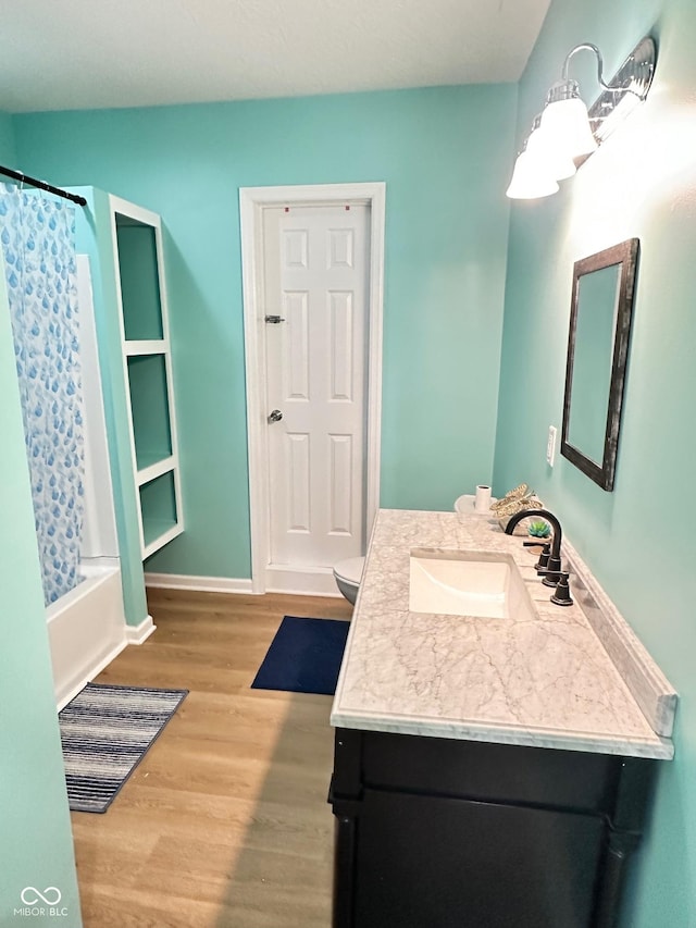 bathroom featuring vanity, shower / bath combo with shower curtain, wood finished floors, and baseboards