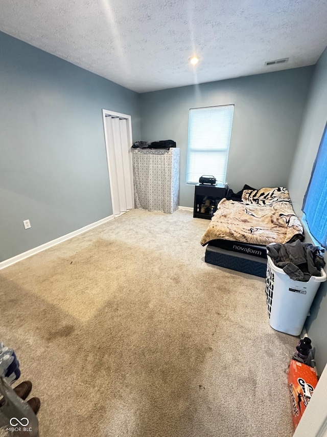 carpeted bedroom with visible vents, baseboards, and a textured ceiling