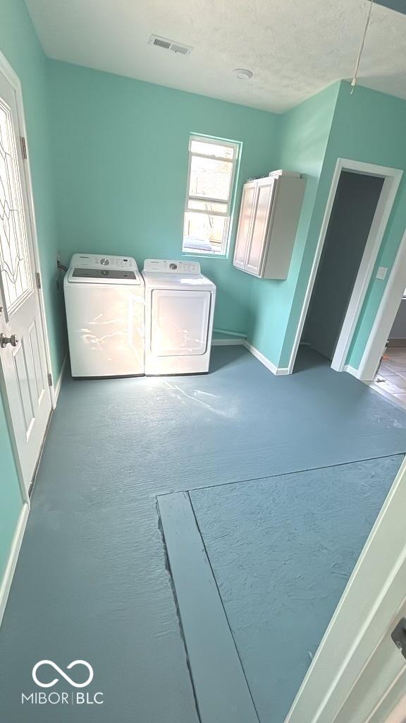 washroom featuring visible vents, washer and dryer, a textured ceiling, baseboards, and laundry area