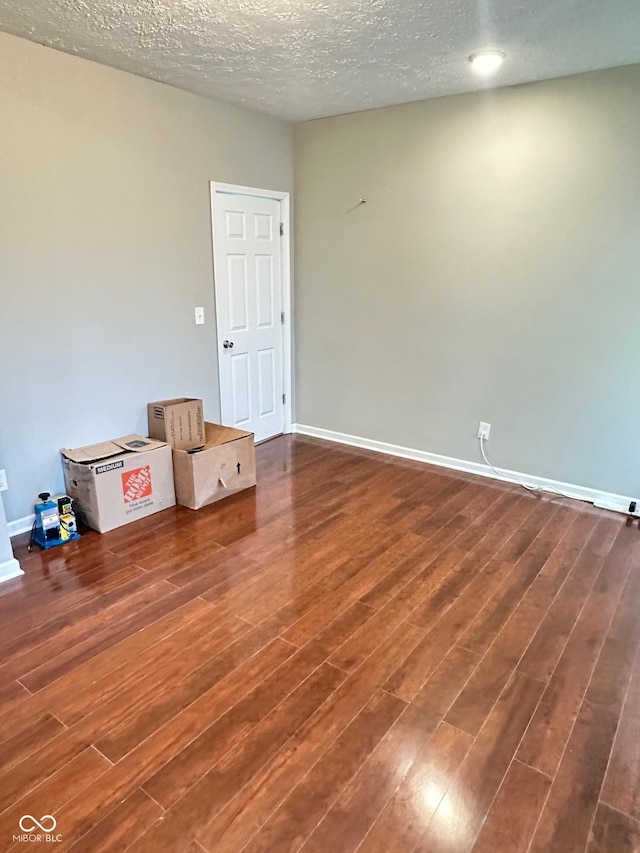 spare room with wood finished floors, baseboards, and a textured ceiling