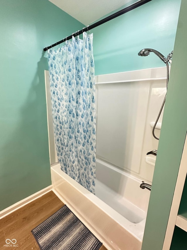 full bathroom featuring wood finished floors, shower / bathtub combination with curtain, baseboards, and visible vents