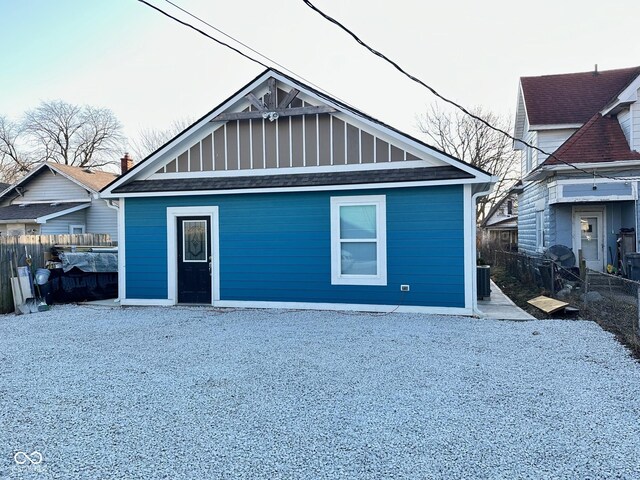 exterior space with cooling unit, board and batten siding, and fence