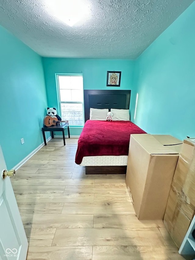 bedroom featuring wood finished floors, baseboards, and a textured ceiling