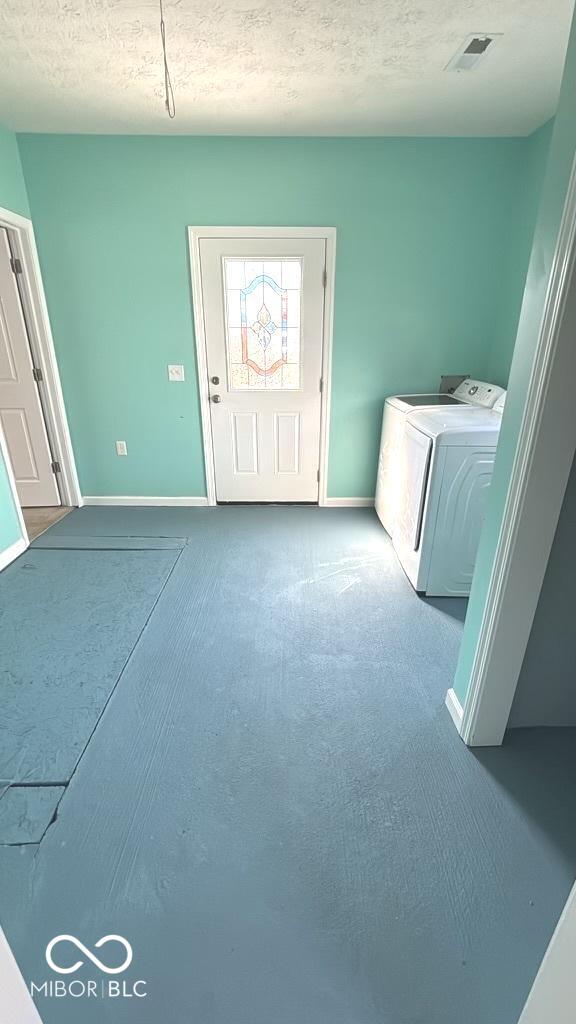 washroom featuring carpet, baseboards, washer and clothes dryer, laundry area, and a textured ceiling