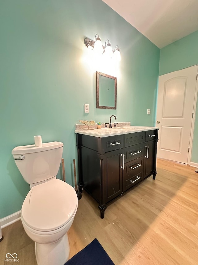 bathroom with vanity, toilet, wood finished floors, and baseboards