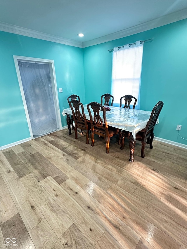 dining space with crown molding, wood finished floors, and baseboards