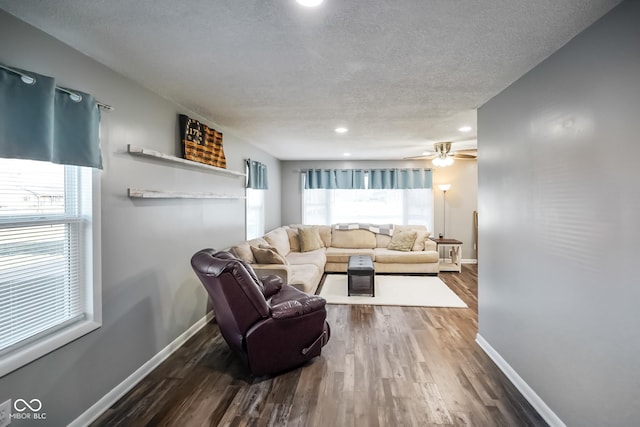 living room featuring ceiling fan, baseboards, a textured ceiling, and dark wood-style floors