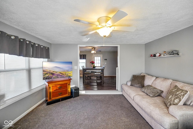 living room with baseboards, ceiling fan, a textured ceiling, and carpet