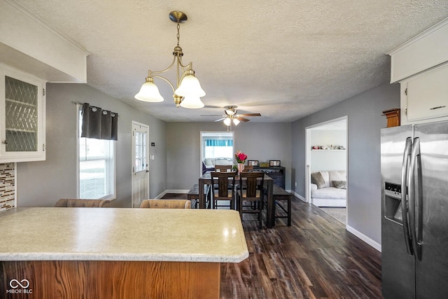 kitchen featuring light countertops, dark wood-type flooring, a textured ceiling, decorative light fixtures, and stainless steel fridge