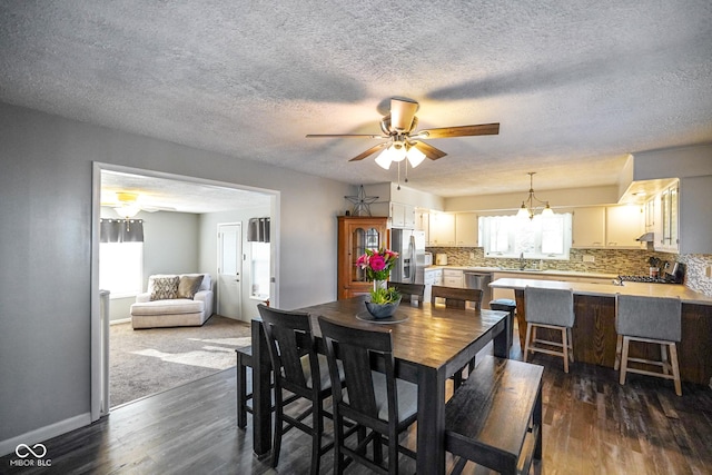 dining area with dark wood-style floors, ceiling fan, a textured ceiling, and baseboards