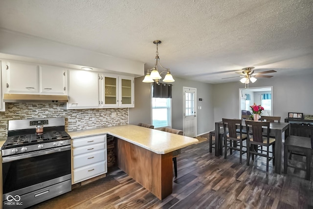 kitchen with dark wood-style floors, stainless steel range with gas cooktop, a peninsula, light countertops, and under cabinet range hood