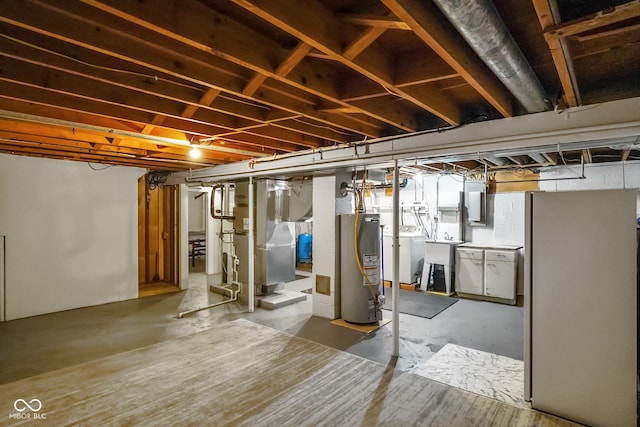 basement with washer and dryer, gas water heater, heating unit, and a sink