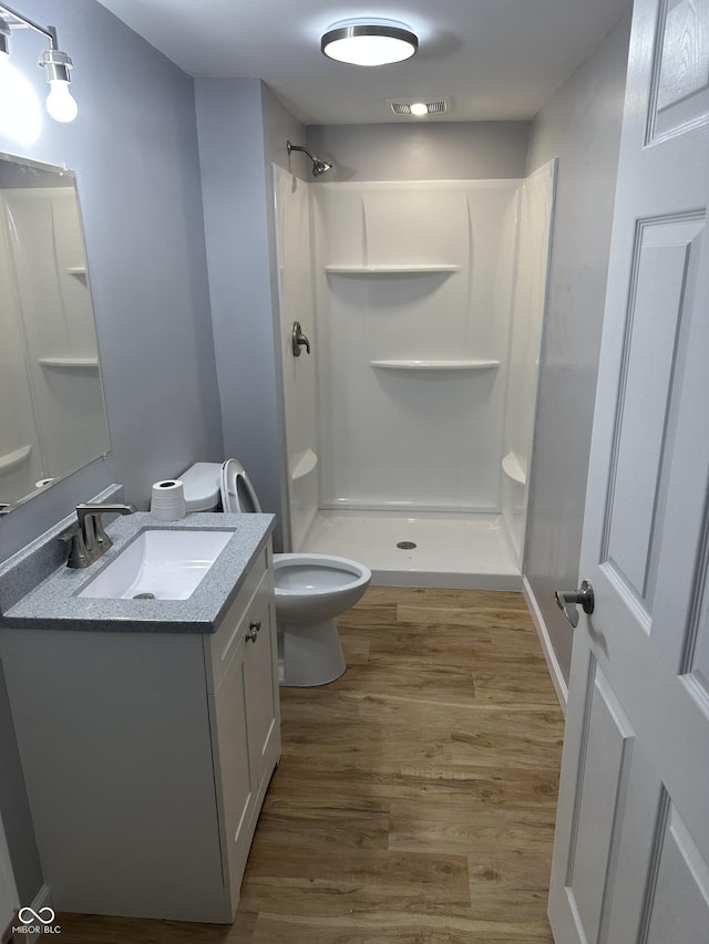 full bathroom featuring visible vents, toilet, wood finished floors, a shower, and vanity