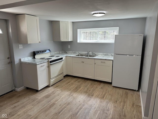 kitchen featuring a sink, white appliances, light wood-style flooring, and white cabinetry