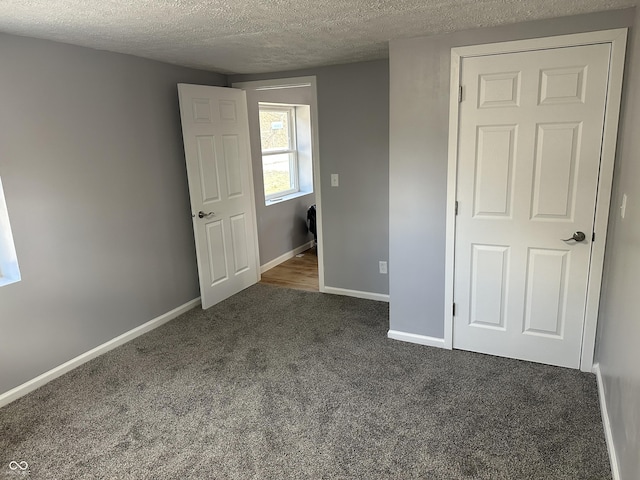 unfurnished bedroom featuring baseboards, carpet floors, and a textured ceiling