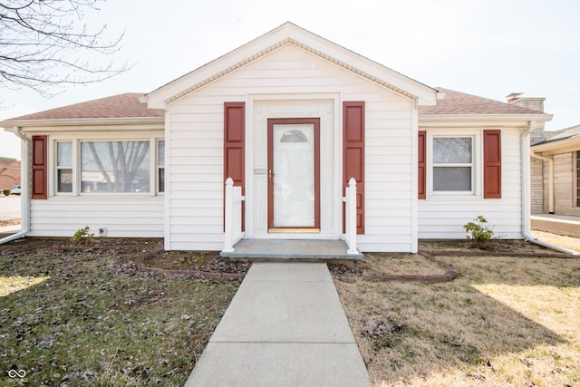 view of front of home featuring a shingled roof and a front yard