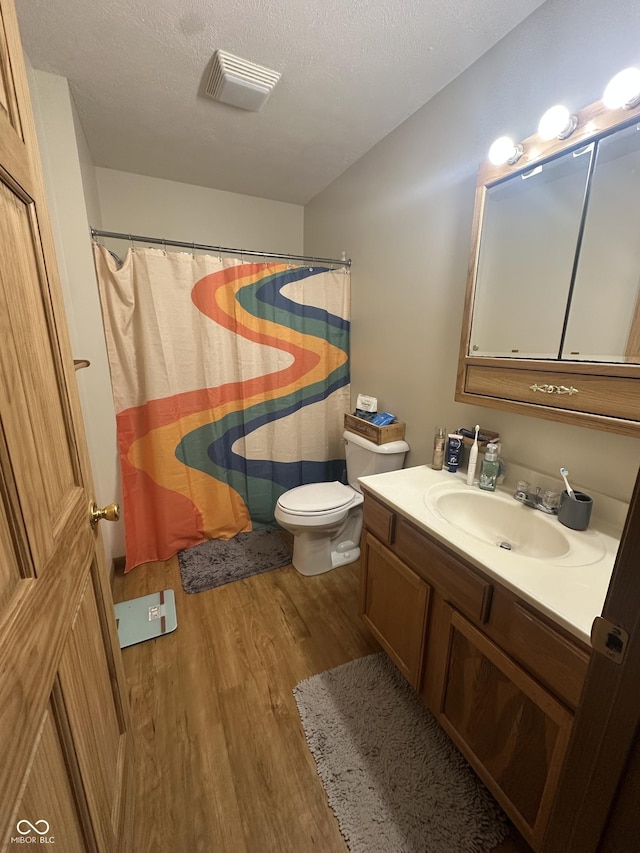8 Gladiator Dr, Waynetown, IN 47990 - full bathroom featuring a textured ceiling, visible vents, toilet, wood finished floors, and vanity