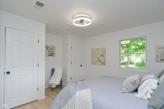 bedroom featuring light wood-type flooring, visible vents, baseboards, and attic access