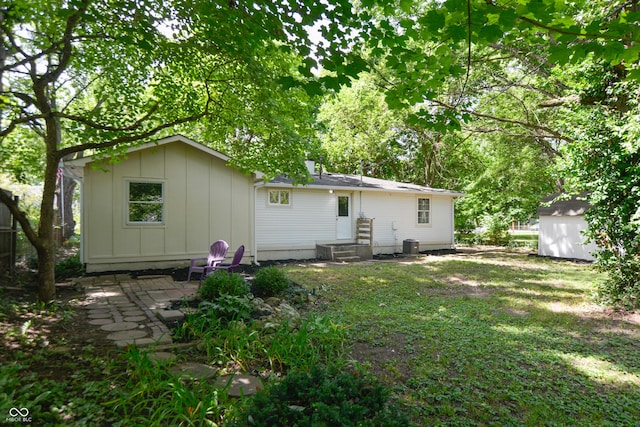 back of property with an outbuilding, central AC, a shed, board and batten siding, and a patio area