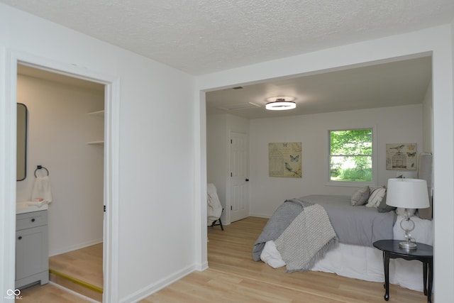 bedroom with light wood-type flooring, baseboards, and a textured ceiling