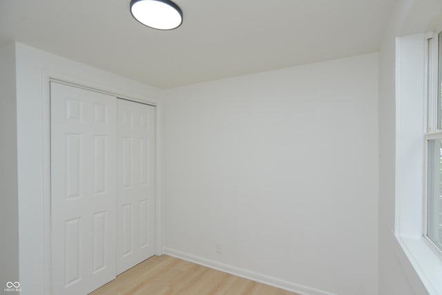 unfurnished bedroom with a closet, light wood finished floors, and baseboards