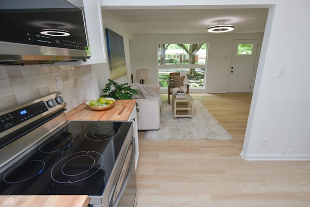 kitchen featuring wood finished floors, baseboards, wooden counters, stainless steel appliances, and backsplash