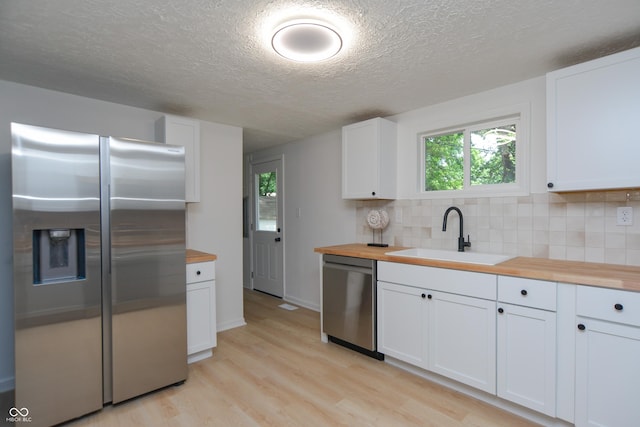 kitchen featuring a sink, butcher block countertops, backsplash, and stainless steel appliances