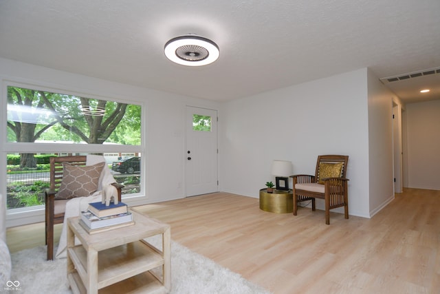 sitting room featuring a textured ceiling, baseboards, visible vents, and light wood-type flooring