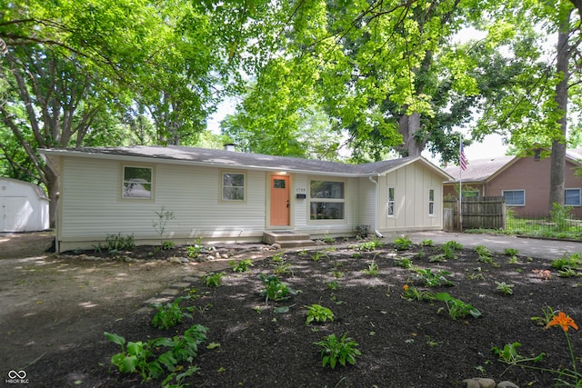 ranch-style home with a storage unit, entry steps, fence, board and batten siding, and an outdoor structure