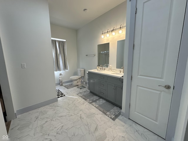 bathroom featuring double vanity, marble finish floor, toilet, and a sink